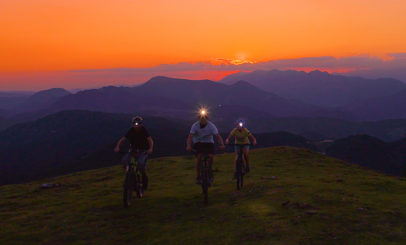 Grupa osób na rowerach podczas wieczornej jazdy po górach